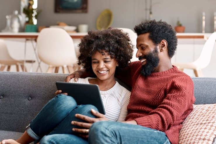 Smiling couple streaming on a tablet on their sofa, illustrating Verbosec Internet home internet